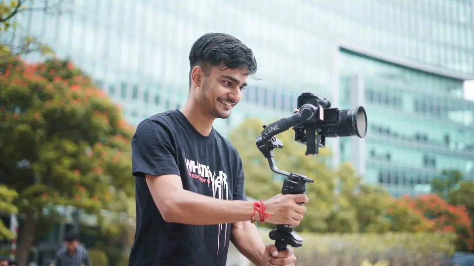 Smiling videographer filming outdoors with a camera on a gimbal